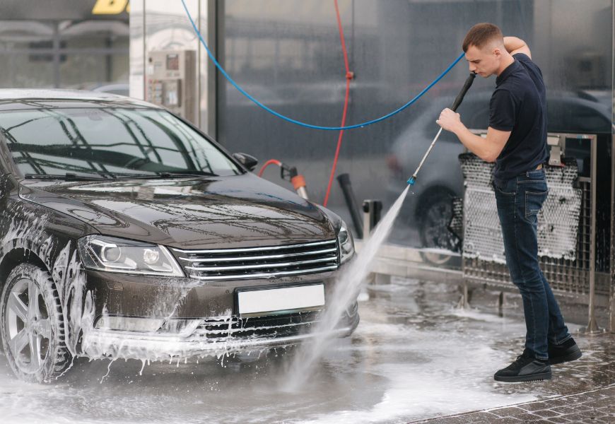 man cleaning car with pressure washer